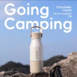Sitarayuri insulated camping bottle with detachable silicone handheld cup and handle in beige color on outdoor rocks